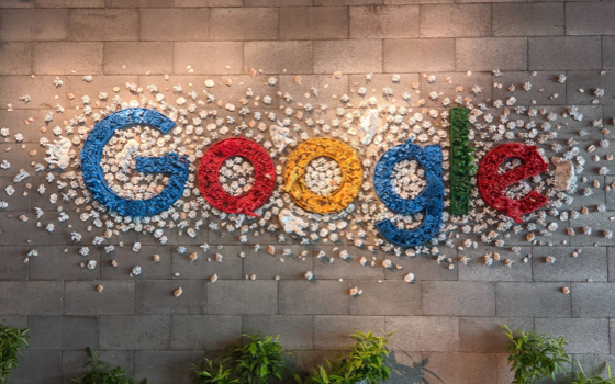 The Google logo made of crumpled paper balls on a stone wall